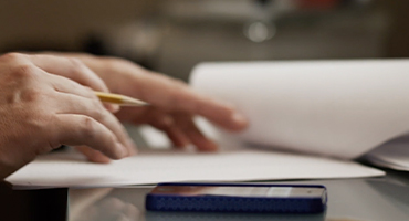 closeup of hands flippling paper and entering numbers into a calculator