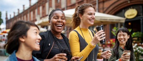 4 young women smiling and walking outside with togo coffee cups