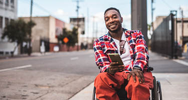 Man sitting outside holding mobile phone and smiling 