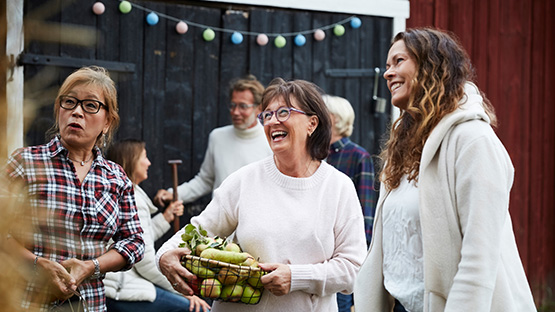 three woman laughing together at an outdoor market