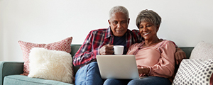 Senior couple sitting on couch watching a laptop