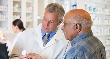 Male pharmacist explaining medication to an older man