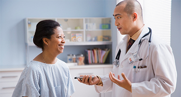 female patient sitting on medical table speaking with male doctor