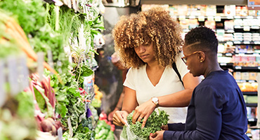 two women shopping in the produce section of a grocery store