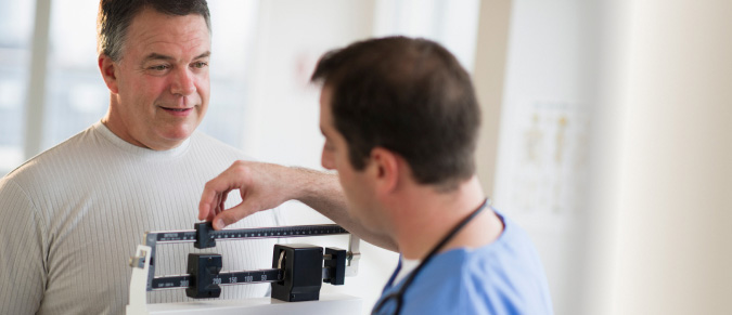 older man being weighed by male medical professional