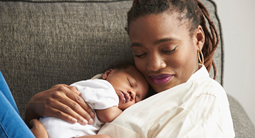 Mother with newborn laying on her chest as she is laying on a couch