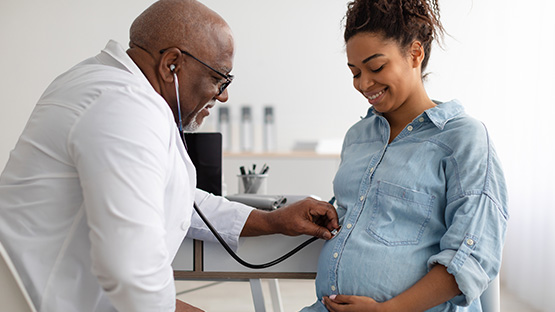 Pregnant woman being examined by a male doctor with a stethoscope