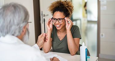 woman trying on glasses with doctor