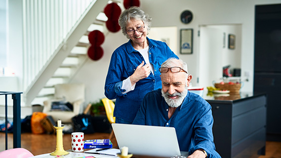 Senior couple smiling while looking at a laptop on a table