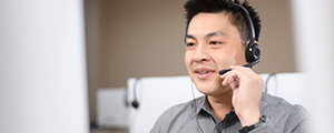 Man in headset sitting at desk speaking with customer