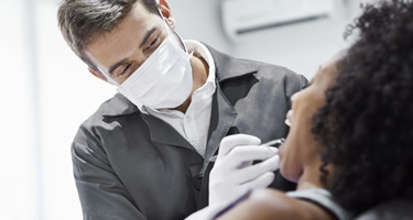 dentist leaning over female patient in dental chair