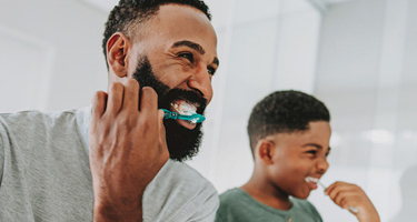 father and son brushing teeth together