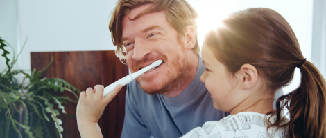 father and daughter brushing teeth in bathroom