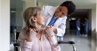 senior woman in wheelchair with nurse pushing her through hospital hallway