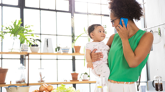 Woman on the phone while holding her baby. 