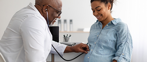 Doctor places a stethoscope on a pregnant woman's belly to listen to her baby's heartbeat. 