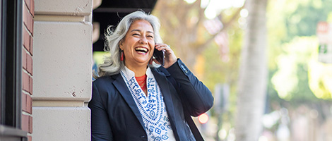 Smiling senior woman talking on mobile phone while leaning against a building outside
